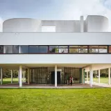 Villa Savoye, capolavoro di Le Corbusier, si erge su pilastri bianchi, con finestre a nastro e forme curve che sfidano la gravità.