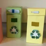 Quattro colorati contenitori per la raccolta differenziata fai da te, con simboli e immagini che indicano cosa gettare.