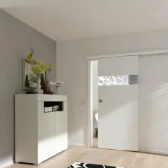 Una moderna porta scorrevole bianca con inserto decorato, perfetta per costruire una porta scorrevole in un ingresso luminoso.