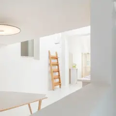 Interni luminosi con tavolo, scala in legno e lampada Umberto Riva.