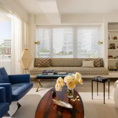 Salotto luminoso con divano geometrico, poltrone blu e lampada art deco.