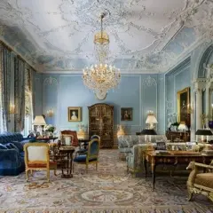 Salotto sontuoso in stile rococò, con soffitto decorato, lampadario di cristallo, tappeto persiano e mobili d'epoca.