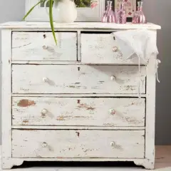 Cassettiera bianca con finitura invecchiata, tipica della tecnica shabby. Dettagli consumati e pomelli in ceramica.
