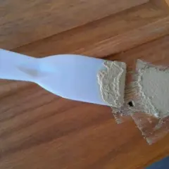 Spatola con stucco per legno fai da te, pronta per riparare un piccolo foro su una superficie di legno.