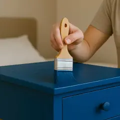 Mano che dipinge un mobile blu con un pennello, mostrando come laccare un mobile per un nuovo look.