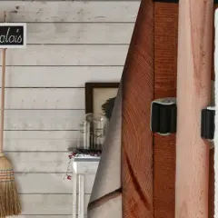 Idee portascope fai da te: tre scope appese a una lavagnetta "Parking à Balais" su parete di legno sbiancato.