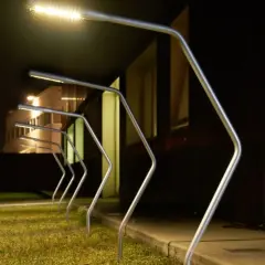Row of modern silver garden lamps with bright LED lights at night.