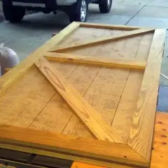 Porta fai da te per esterno in legno grezzo, con rinforzi a X, pronta per essere installata.