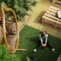 Bambina gioca su prato artificiale in un balcone con **giardini pensili**, sedia sospesa e tavolino fai-da-te.
