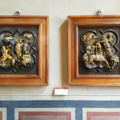 Due bassorilievi dorati incorniciati in legno, opere di Brunelleschi, raffigurano scene bibliche con figure umane e animali.