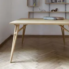 Tavolo pieghevole fai da te in legno chiaro, con gambe a incastro e piano squadrato. Due ciotole decorative sul piano.
