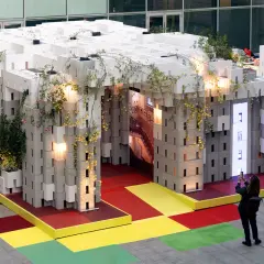 Installazione modulare con piante rampicanti, un'anticipazione della design week milano 2026. Una persona scatta una foto.