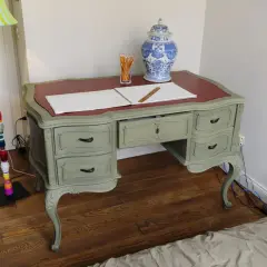 Scrivania in stile shabby chic, con finitura chalk paint fai da te. Penzoli, un righello e un vaso decorato completano la scena.