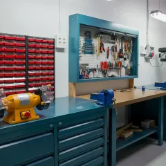 Un'officina ben organizzata con morsa, trapano a colonna, mola e tanti cassetti per idee officina fai da te.