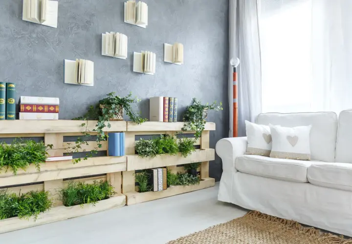 Pareti con bancali che ospitano piante verdi e libri, creando un angolo lettura naturale e accogliente.