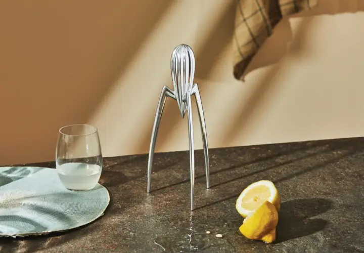Spremiagrumi iconico di Philippe Starck, un bicchiere di succo e limoni freschi su un piano di lavoro.