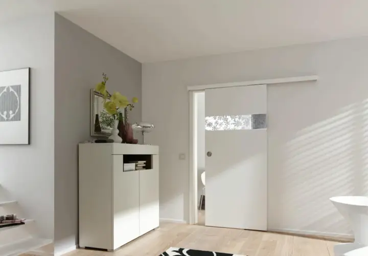Una moderna porta scorrevole bianca con inserto decorato, perfetta per costruire una porta scorrevole in un ingresso luminoso.