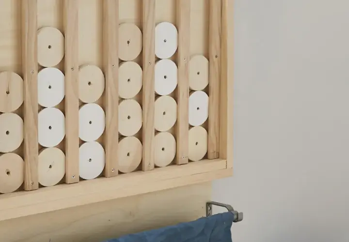 Un gioco da tavolo fai da te in legno, con dischi bianchi e naturali che scorrono su binari verticali.