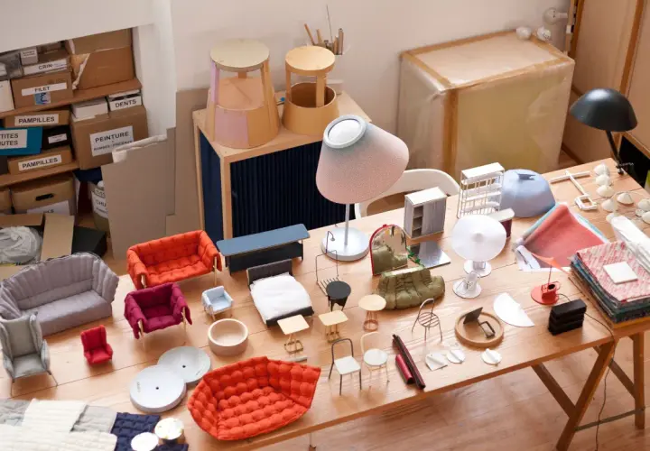 Modelli di mobili in miniatura, tessuti e materiali da artigianato disposti su un tavolo di legno. Un'ispirazione per creare, inga sempé.