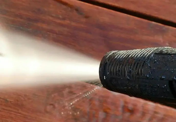 Ugello idropulitrice spruzza acqua su un deck in legno per eliminare odore vernice legno.