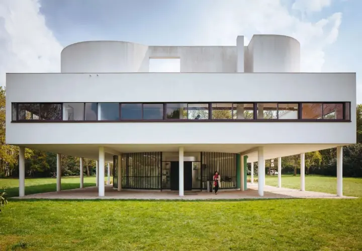 Villa Savoye, capolavoro di Le Corbusier, si erge su pilastri bianchi, con finestre a nastro e forme curve che sfidano la gravità.