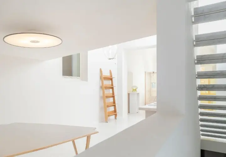 Interni luminosi con tavolo, scala in legno e lampada Umberto Riva.