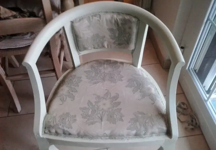 Vecchia poltrona in attesa di un restyling shabby chic. Tessuto floreale chiaro e struttura bianca da rinnovare.