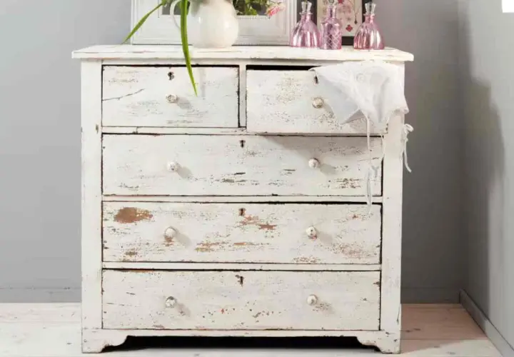 Cassettiera bianca con finitura invecchiata, tipica della tecnica shabby. Dettagli consumati e pomelli in ceramica.