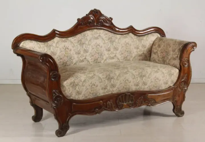 Divano in legno intagliato, con tessuto floreale, in **stile Luigi Filippo**. Un pezzo d'antiquariato che evoca eleganza.
