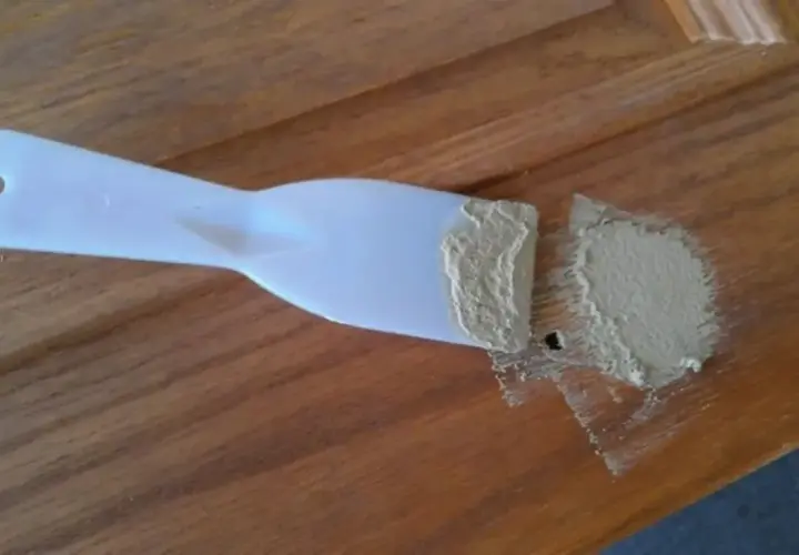 Spatola con stucco per legno fai da te, pronta per riparare un piccolo foro su una superficie di legno.