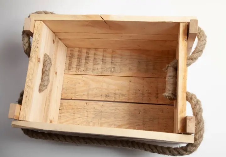 Una cassetta in legno grezzo con manici in corda, perfetta per chi vuole imparare come costruire una cassetta in legno.