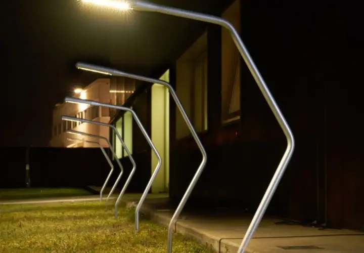 Row of modern silver garden lamps with bright LED lights at night.