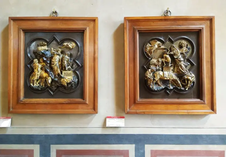 Due bassorilievi dorati incorniciati in legno, opere di Brunelleschi, raffigurano scene bibliche con figure umane e animali.