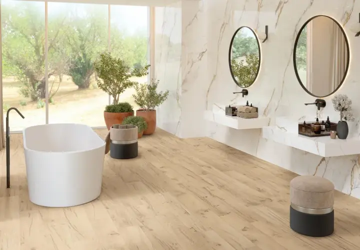 Bagno luminoso con vasca freestanding, piante verdi e specchi ovali. Un'oasi di relax in stile bohemien, con pavimenti in legno chiaro e dettagli in marmo.