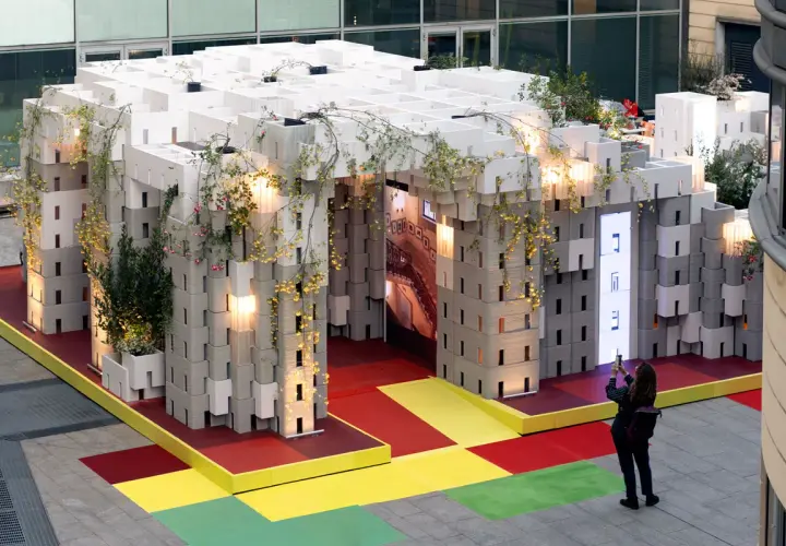 Installazione modulare con piante rampicanti, un'anticipazione della design week milano 2026. Una persona scatta una foto.