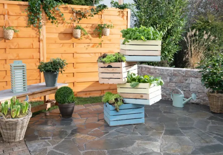 Fioriera fai da te con cassette di legno colorate impilate, piene di verdure fresche. Un'idea creativa per il tuo orto.