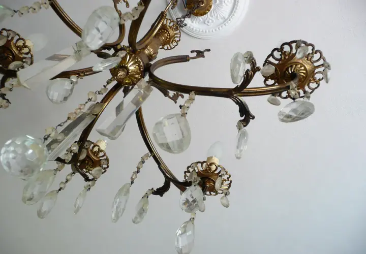 Un vecchio lampadario in ottone con pendenti di cristallo, un'idea per come riutilizzare un vecchio lampadario.