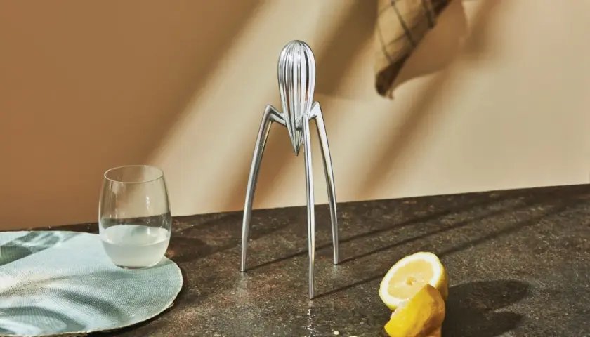 Spremiagrumi iconico di Philippe Starck, un bicchiere di succo e limoni freschi su un piano di lavoro.