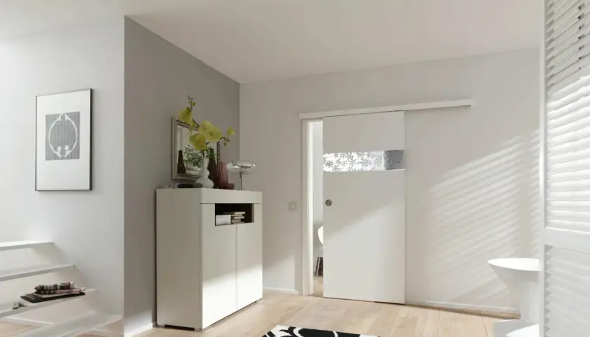 Una moderna porta scorrevole bianca con inserto decorato, perfetta per costruire una porta scorrevole in un ingresso luminoso.