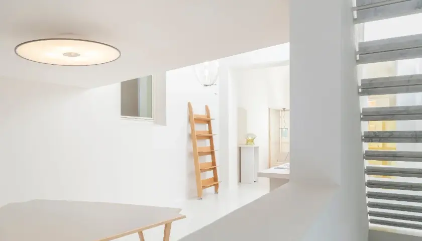 Interni luminosi con tavolo, scala in legno e lampada Umberto Riva.