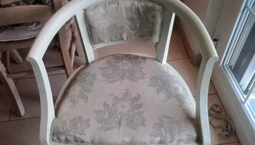 Vecchia poltrona in attesa di un restyling shabby chic. Tessuto floreale chiaro e struttura bianca da rinnovare.
