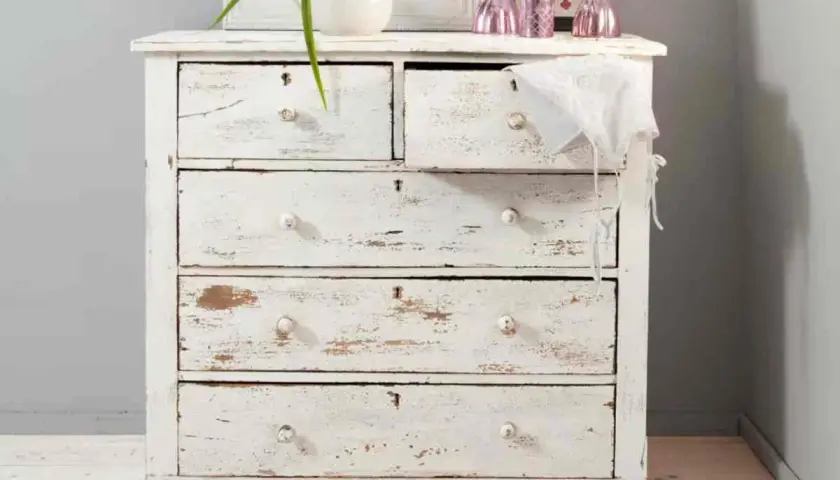 Cassettiera bianca con finitura invecchiata, tipica della tecnica shabby. Dettagli consumati e pomelli in ceramica.