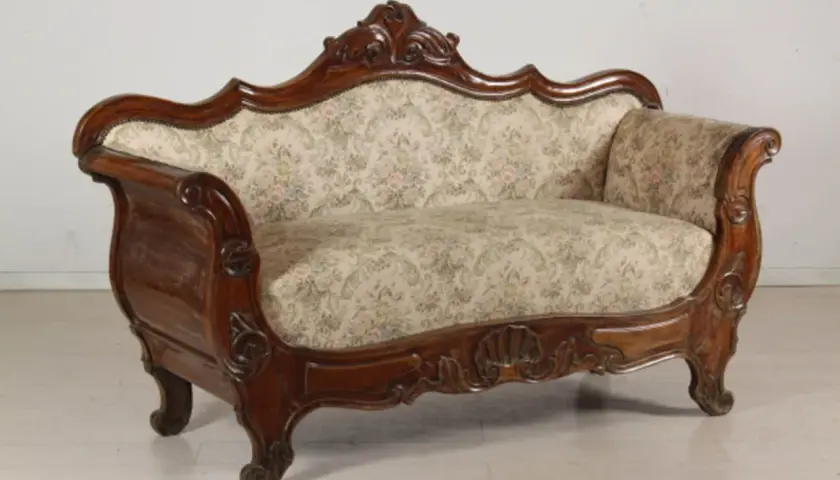Divano in legno intagliato, con tessuto floreale, in **stile Luigi Filippo**. Un pezzo d'antiquariato che evoca eleganza.