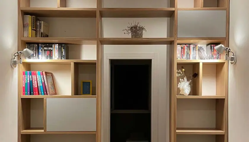 Libreria in legno con libri, vasi e faretti. Un'idea per costruire una libreria funzionale e di design.