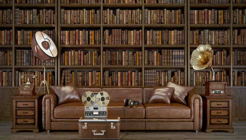 Un salotto in stile dark academia con divano in pelle, libreria imponente e oggetti vintage come un giradischi e un registratore a bobine.