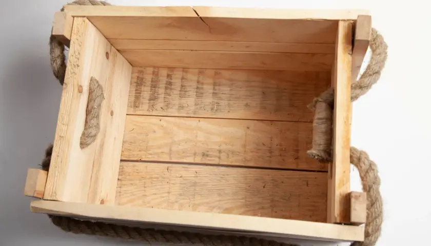Una cassetta in legno grezzo con manici in corda, perfetta per chi vuole imparare come costruire una cassetta in legno.