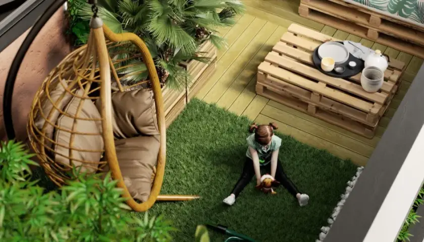 Bambina gioca su prato artificiale in un balcone con **giardini pensili**, sedia sospesa e tavolino fai-da-te.