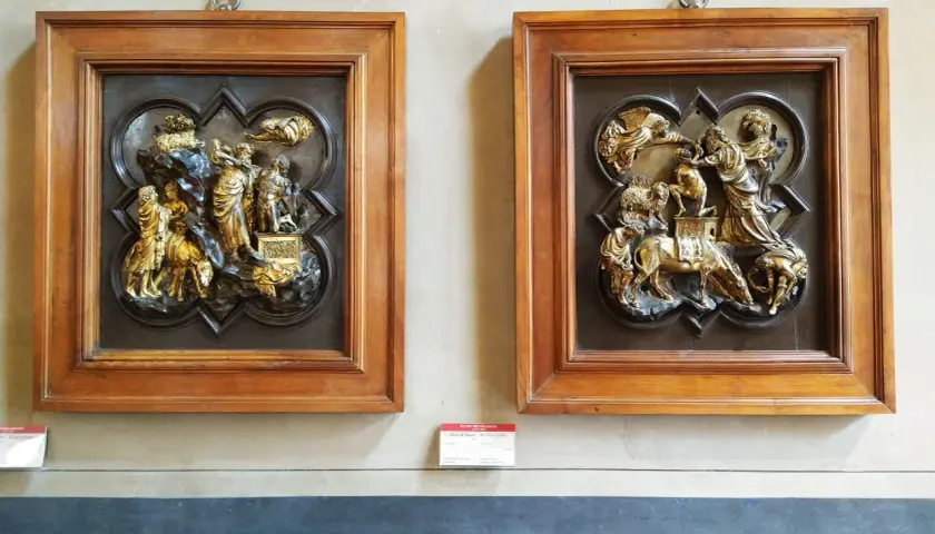 Due bassorilievi dorati incorniciati in legno, opere di Brunelleschi, raffigurano scene bibliche con figure umane e animali.