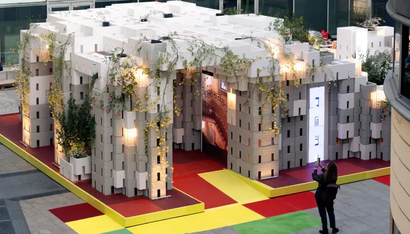 Installazione modulare con piante rampicanti, un'anticipazione della design week milano 2026. Una persona scatta una foto.
