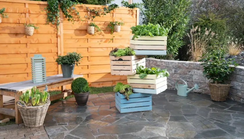 Fioriera fai da te con cassette di legno colorate impilate, piene di verdure fresche. Un'idea creativa per il tuo orto.
